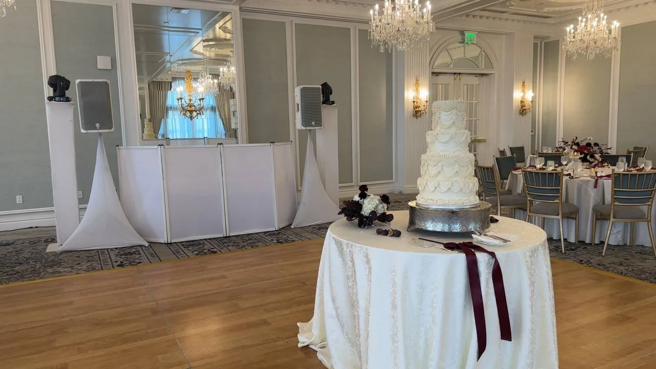 Elegant white DJ facade with twin speakers and moving head lights beside the wedding cake table at Hotel Carmichael, Carmel Indiana — Layaly Indiana